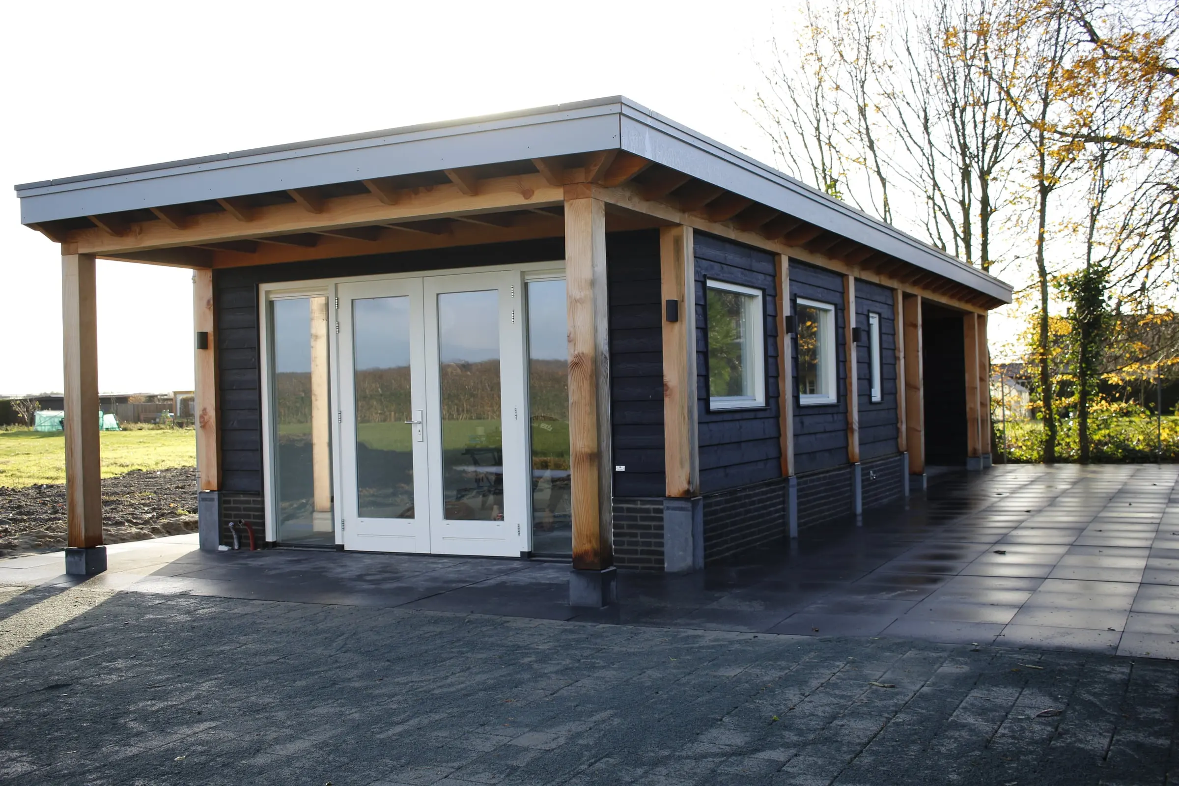 Zwart tuinhuis met openslaande deuren en een overkapping
