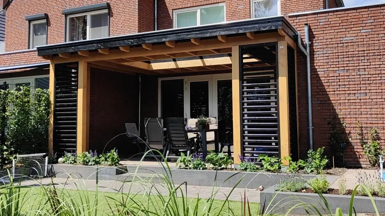Veranda tegen de achtergevel met een zwarte lamellenwand en een zithoek, in Renkum