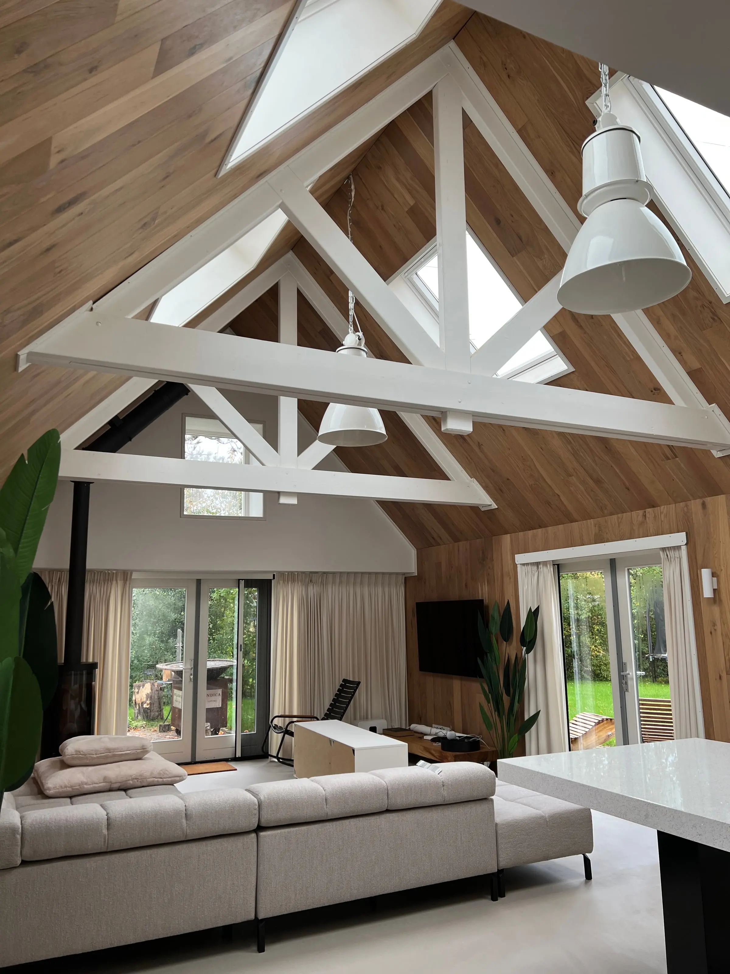 Woonkamer met wit geschilderde houten spanten onder de open nok, in Wageningen